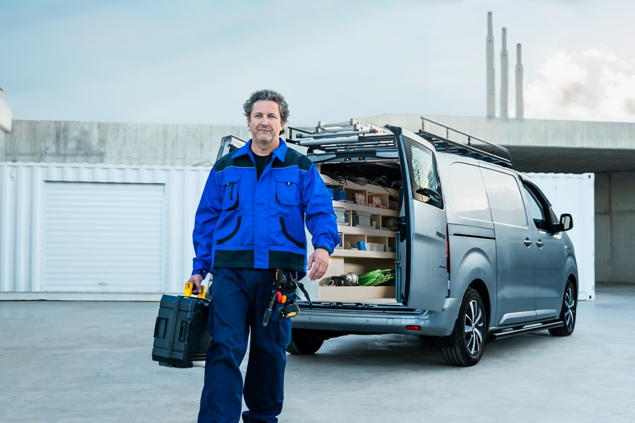 Professional walking away from open back of Toyota Proace with tools in hand